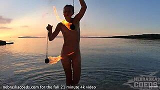 This adorable girl does nude fire dancing on the beach at sunset.