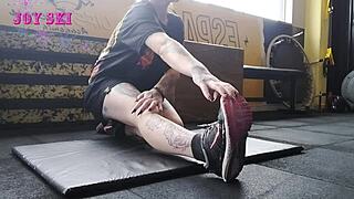 this alternative girl with tattoos stretches at the gym