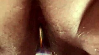 She masturbates her hairy pussy with a glass dildo up close