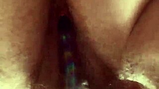 She masturbates her hairy pussy with a glass dildo up close