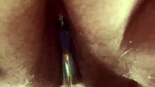 She masturbates her hairy pussy with a glass dildo up close