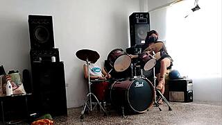 They play the drums for her. She dances stripping and showing her ass.