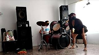 They play the drums for her. She dances stripping and showing her ass.